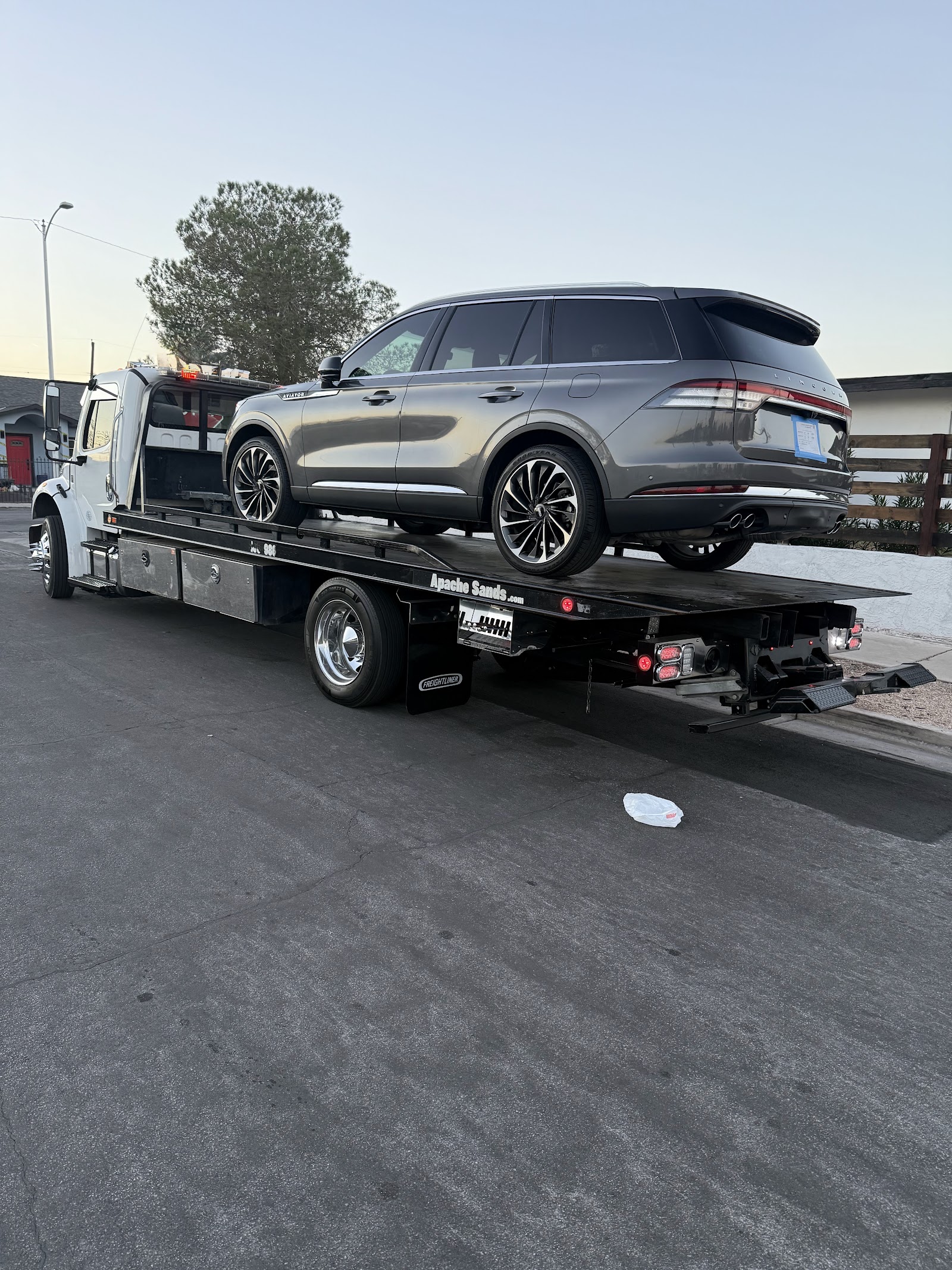 Lincoln Aviator SUV secured on a flatbed tow truck at dusk