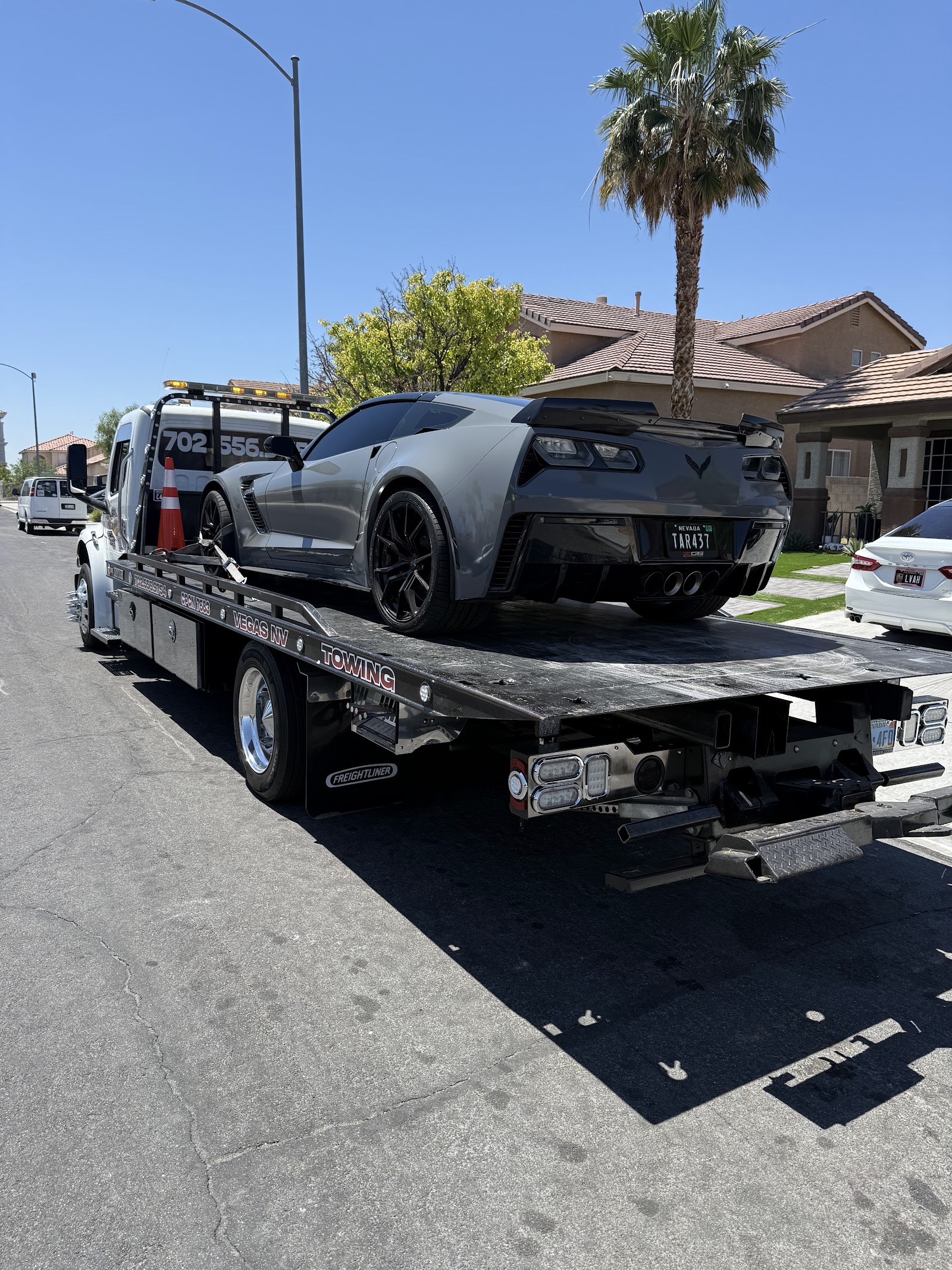 Gray Chevrolet Corvette Z06 loaded on a Vegas NV Towing flatbed in a residential neighborhood